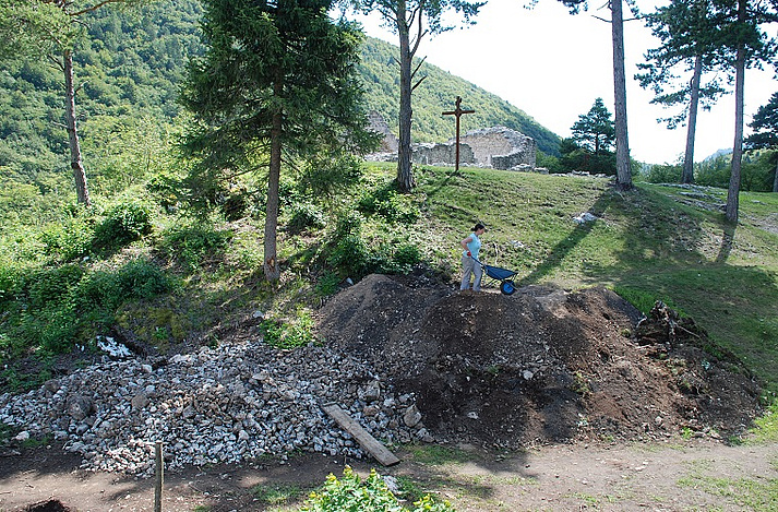 Aushubmaterial wird nach Steinen und Erde getrennt deponiert, um später wieder rückgefüllt zu werden. Im Hintergrund die Kirche.